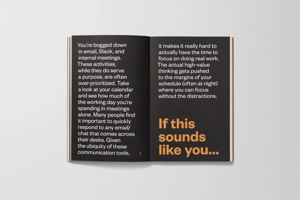 Open book displaying text about work emails, internal meetings, and focusing on real work against a grey studio backdrop.