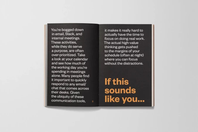 Open book displaying text about work emails, internal meetings, and focusing on real work against a grey studio backdrop.