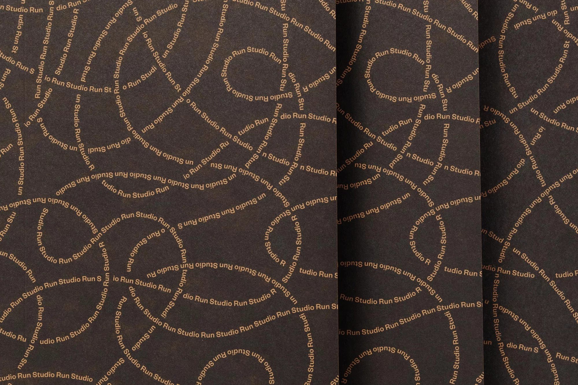 Abstract background with swirling tan text of 'Studio Run' on a dark brown textured surface, creating a dynamic and patterned visual.