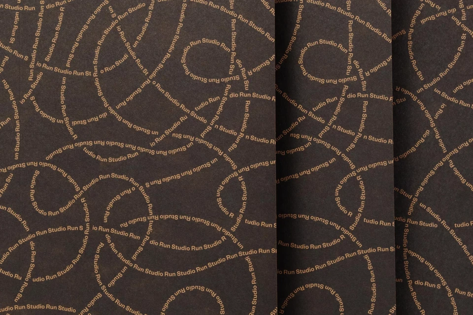 Abstract background with swirling tan text of 'Studio Run' on a dark brown textured surface, creating a dynamic and patterned visual.