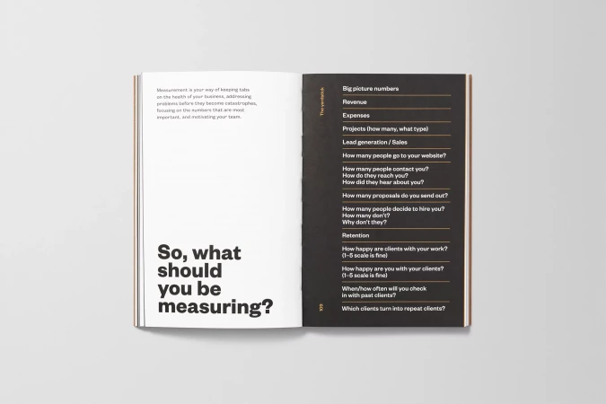 Open book on a white surface showing a list of questions and business metrics on one page and a question on the other.