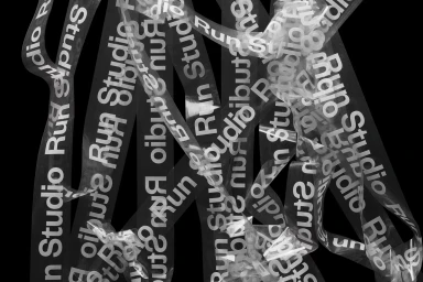Transparent tape with repeating white typography reading Run Studio arranged vertically against a deep black background