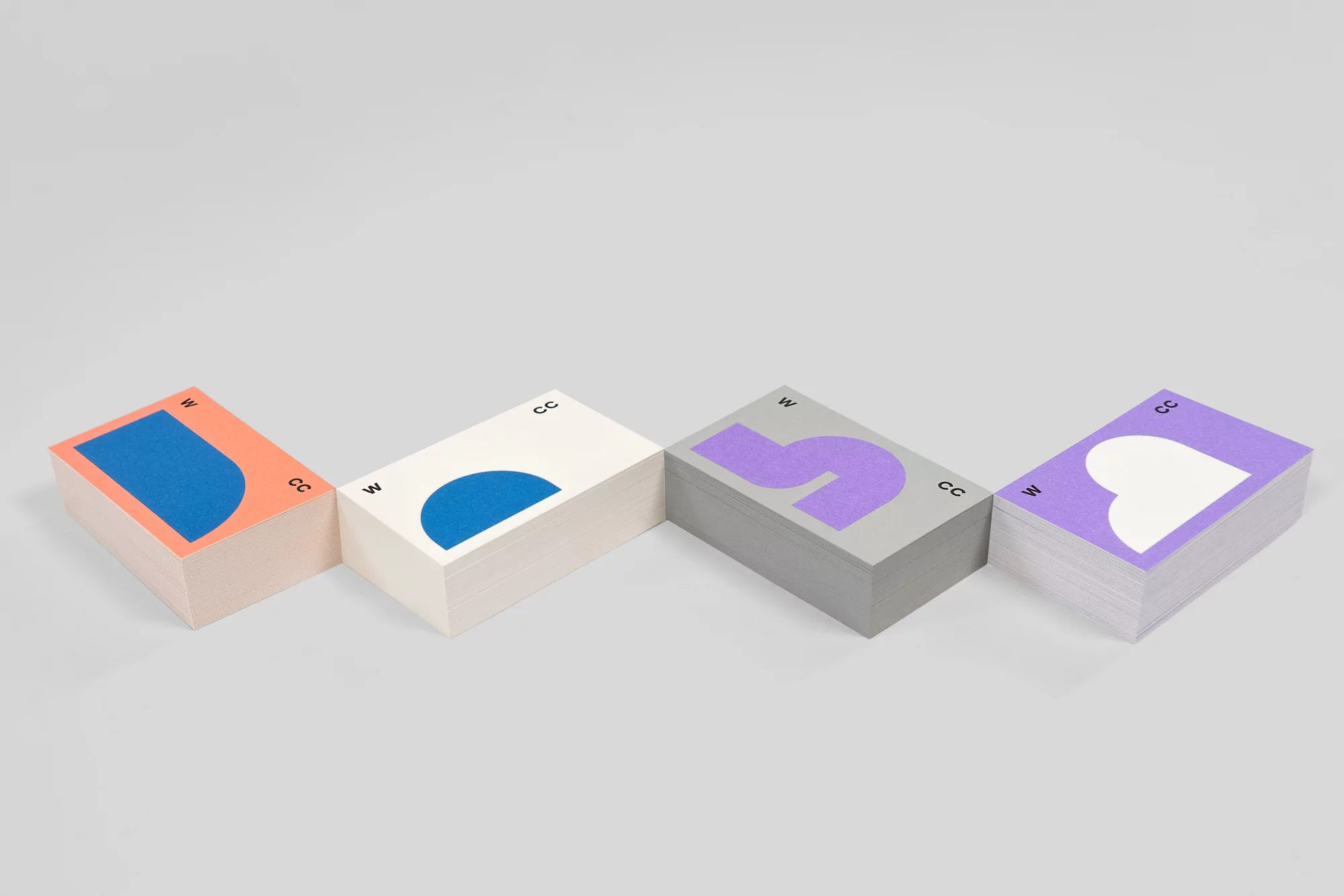 Stacks of white cards with blue, orange, and purple designs are arranged on a gray background in a studio product shot.