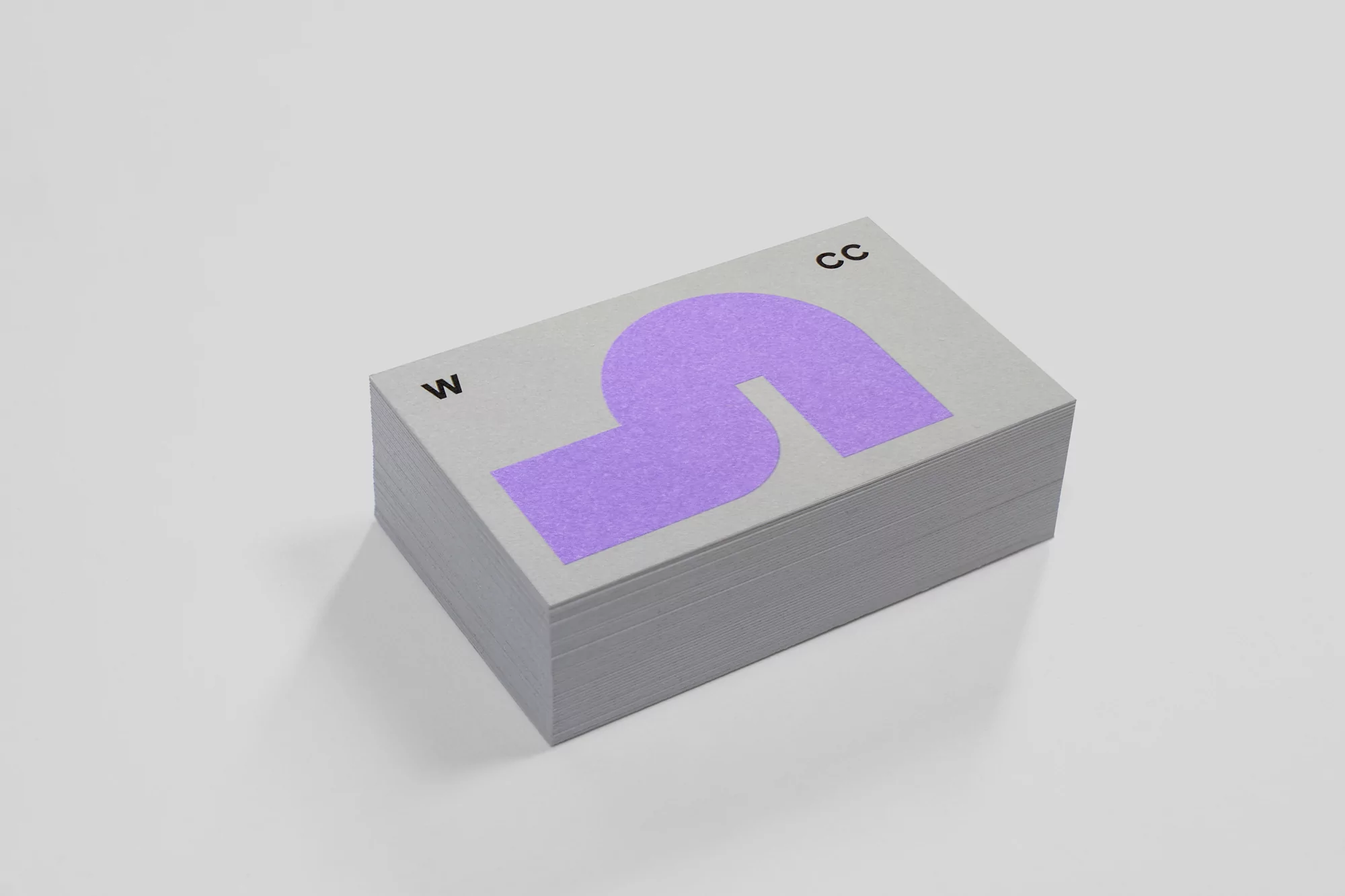 Stack of gray business cards with purple abstract letter-S shape and black text, set against a plain white background.