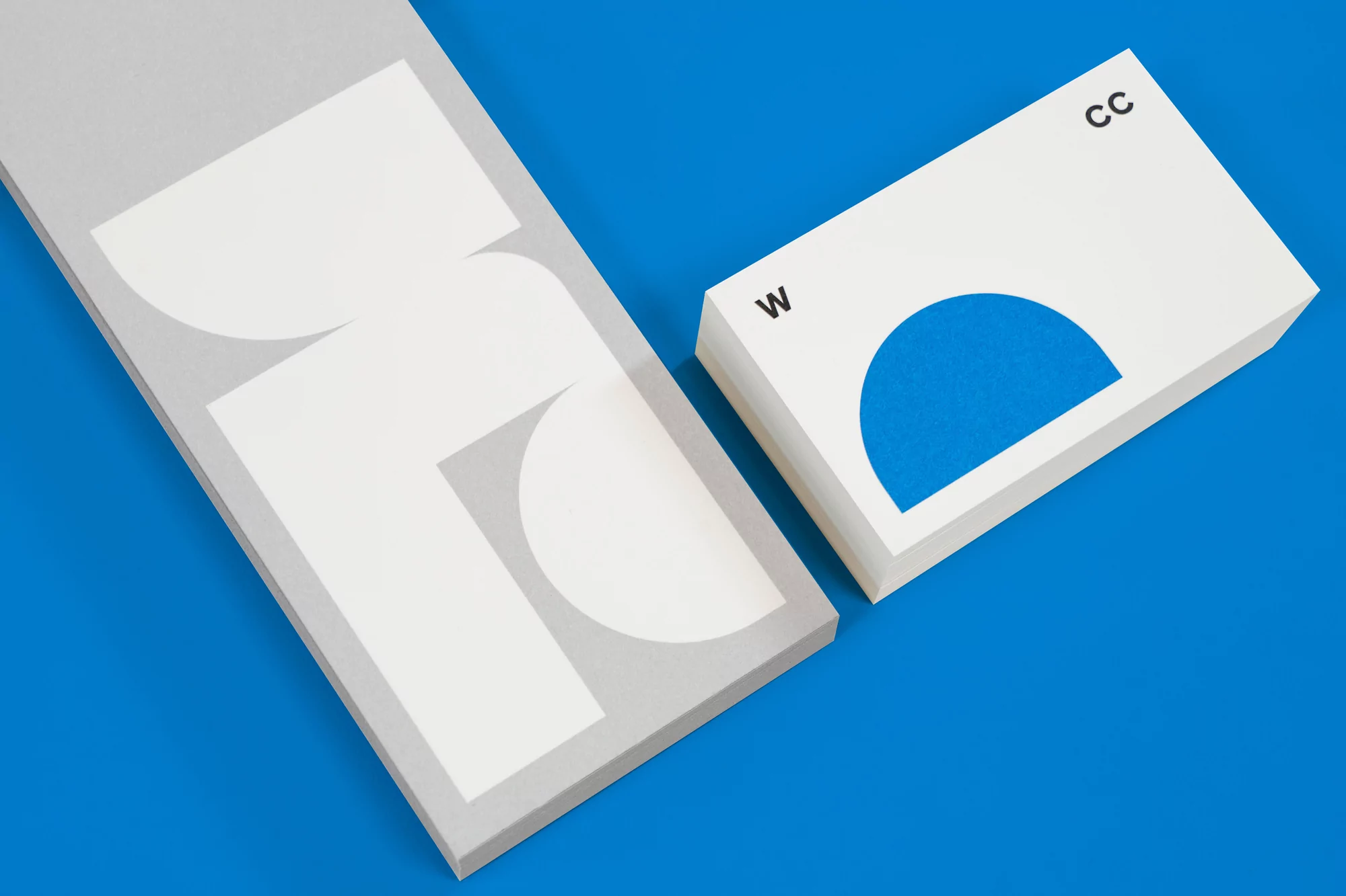Geometric shapes and letters in white, grey, and blue on a blue background, creating an abstract design on stationery.