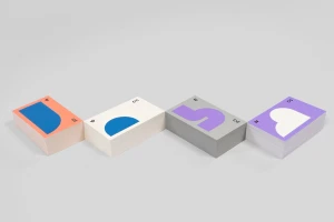 Four stacks of business cards with geometric colour-blocked prints arranged on a seamless white surface.