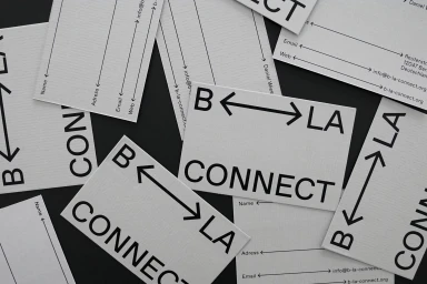 Scattered white business cards with black typography and directional arrows on dark surface