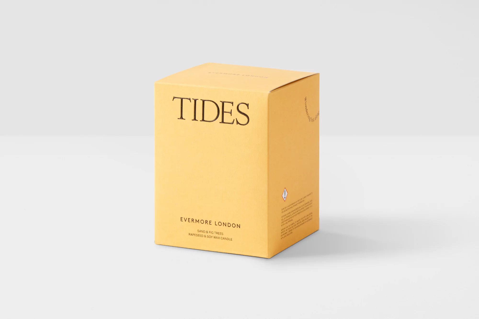 Studio shot of a yellow Evermore London Tides candle box, featuring black text and minimalist design on a light grey background.