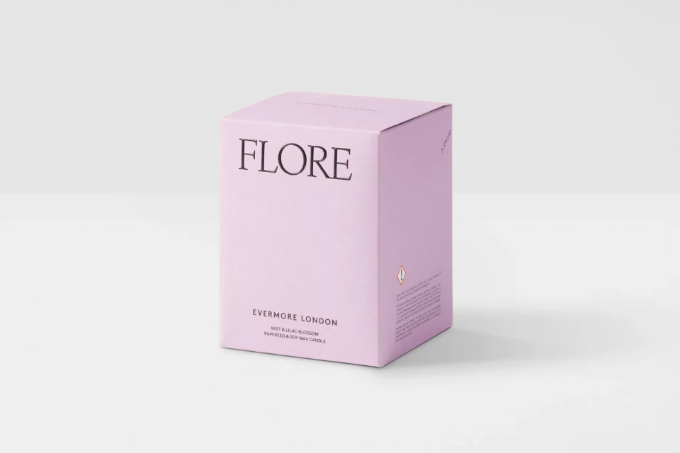 Studio shot of a light-purple square box of 'FLORE Evermore London' mist and lilac blossom rapeseed and soy wax candle on a white background.