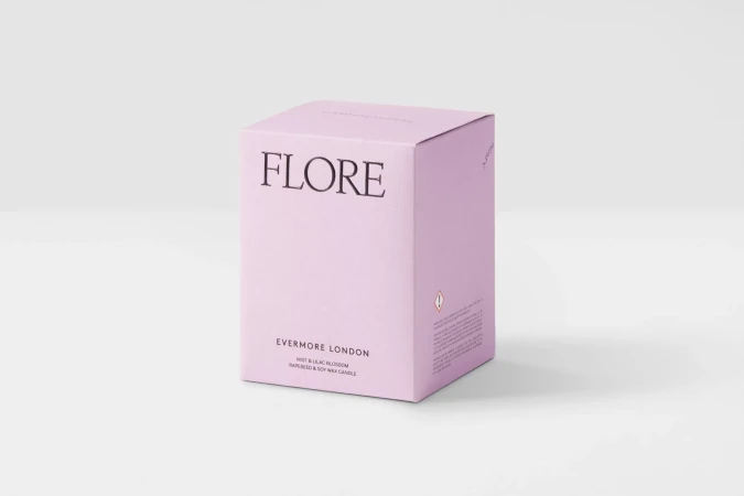 Studio shot of a light-purple square box of 'FLORE Evermore London' mist and lilac blossom rapeseed and soy wax candle on a white background.