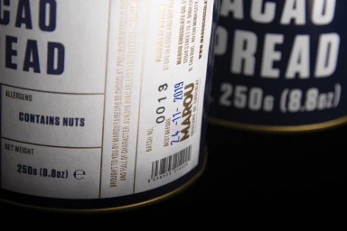 Close-up macro shot of product packaging for Marou cacao spread showing typography and details against a dark background