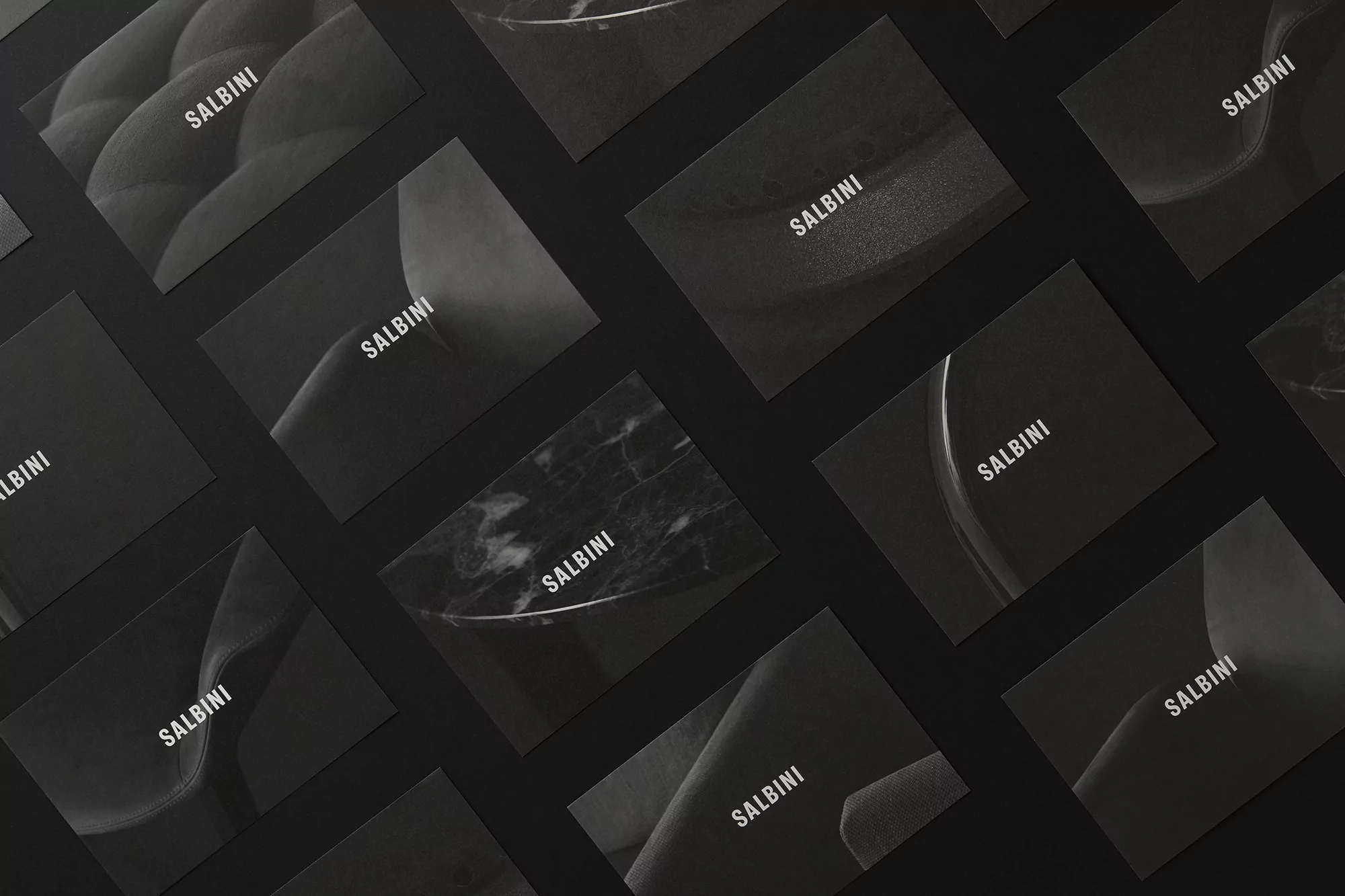 Multiple business cards with the name SALBINI in a diagonal, repeating pattern on a solid black background, creating a minimalist aesthetic.