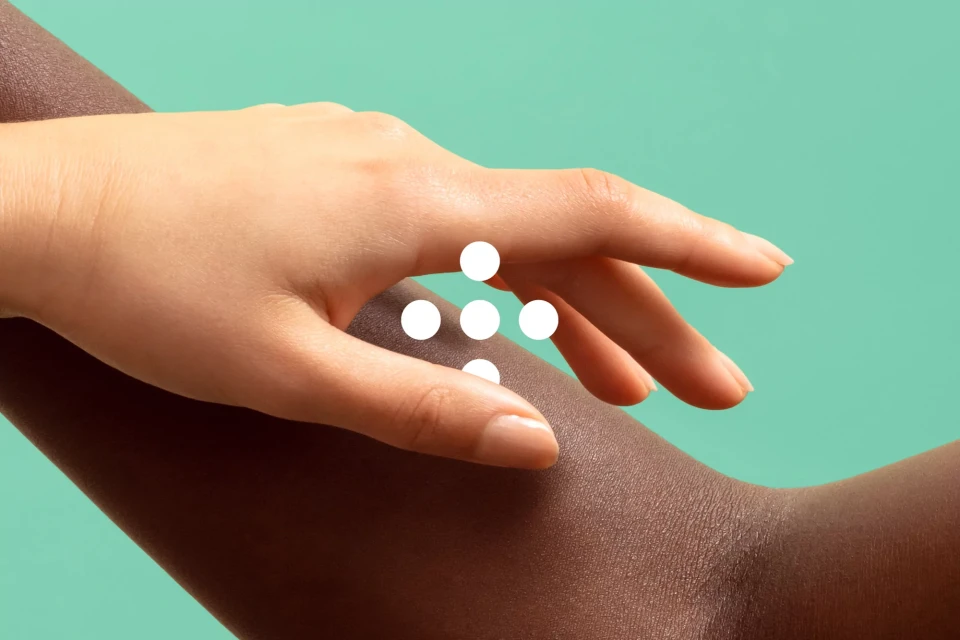 Close-up of two adult hands with contrasting skin tones, one light and one dark, touching against a solid teal background.