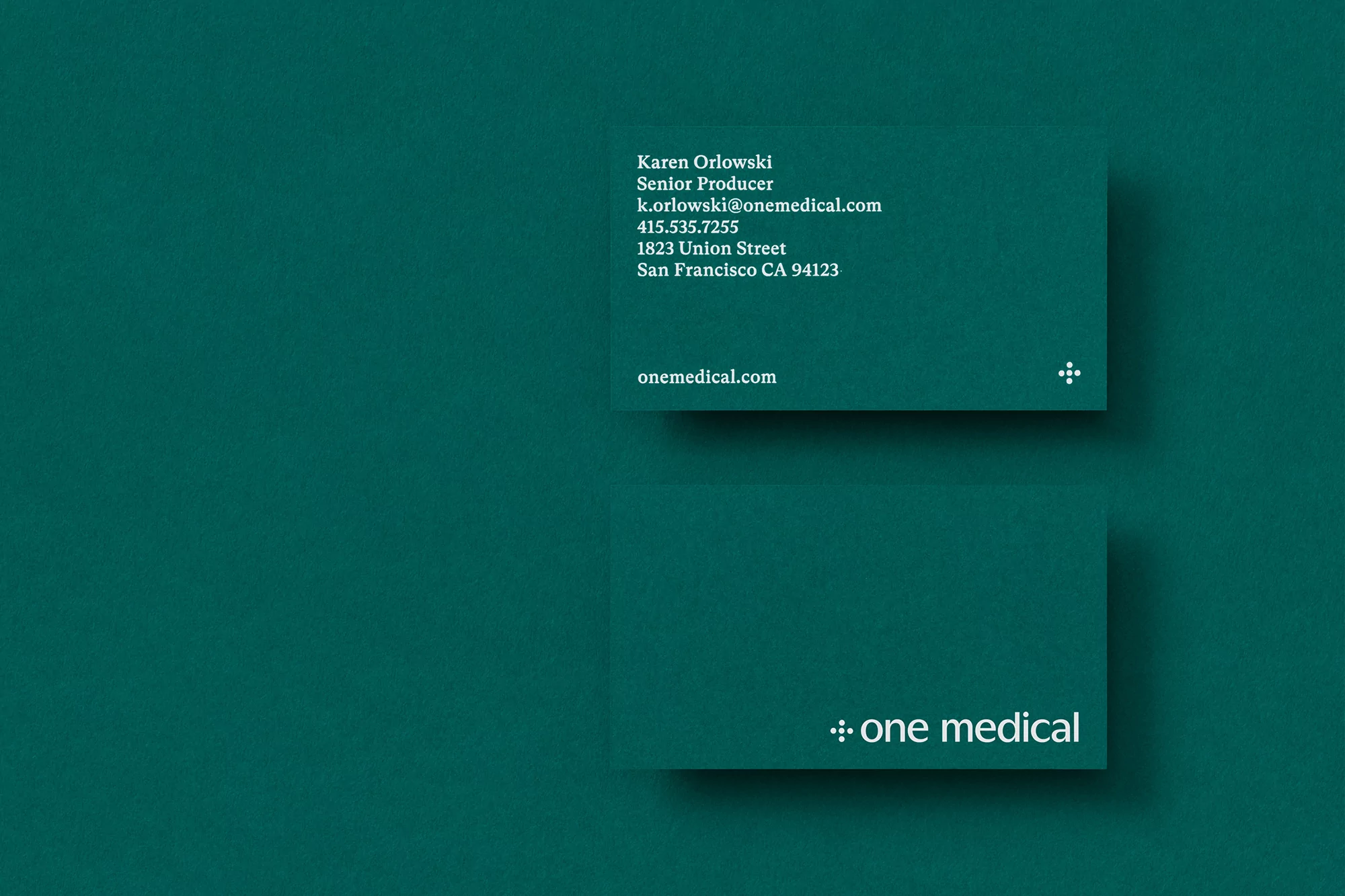 Two business cards with text for Karen Orlowski, Senior Producer, on top of a green-colored background. Brand logo visible on both cards.