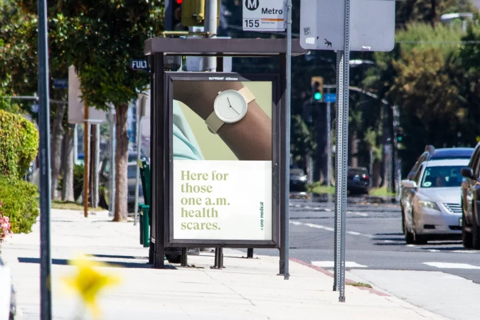Outdoor bus stop advertisement featuring a person wearing a wristwatch, promoting health services against an urban street background.