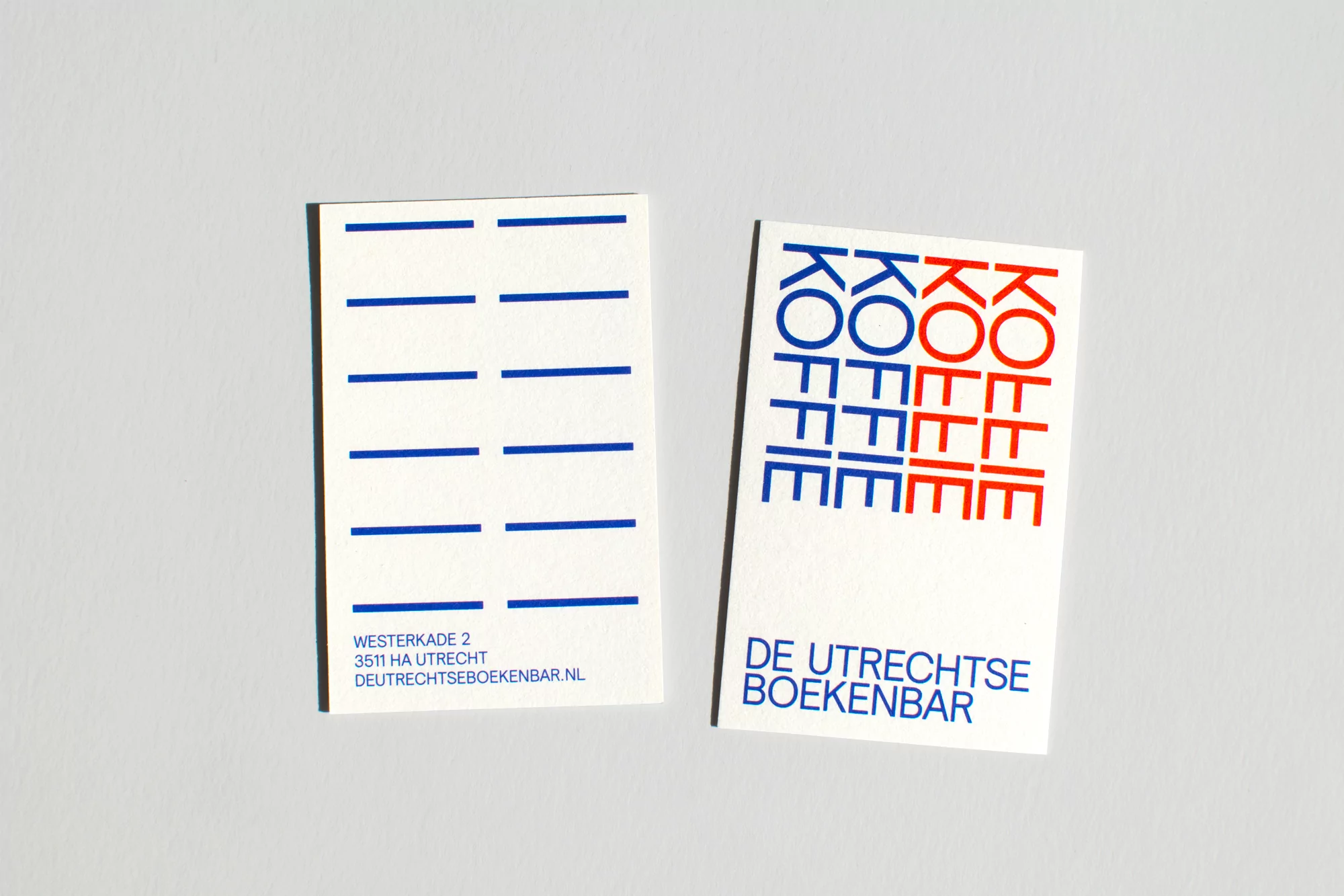 Two white business cards side by side on a white background. The cards feature a modern design with blue and red graphics and text.