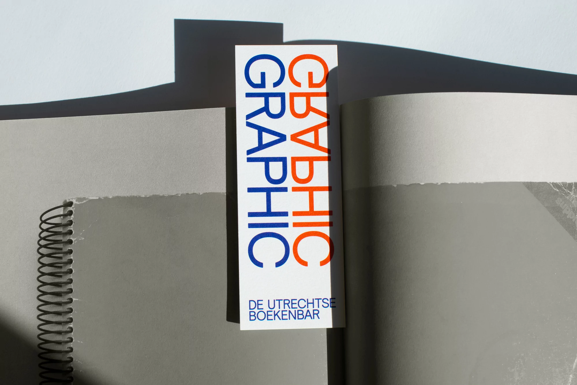 Graphic design publication featuring open notebook and blue and orange text reading 'Graphic' with a bright, contrasted lighting.
