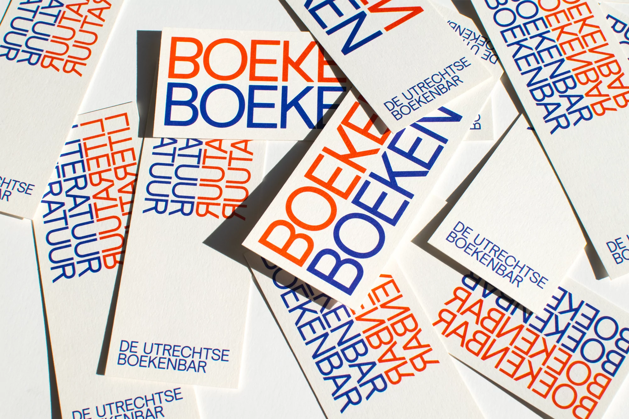 Collection of white bookmarks with bold, colorful text 'BOEKEN' scattered across a white surface, creating a visually striking pattern.