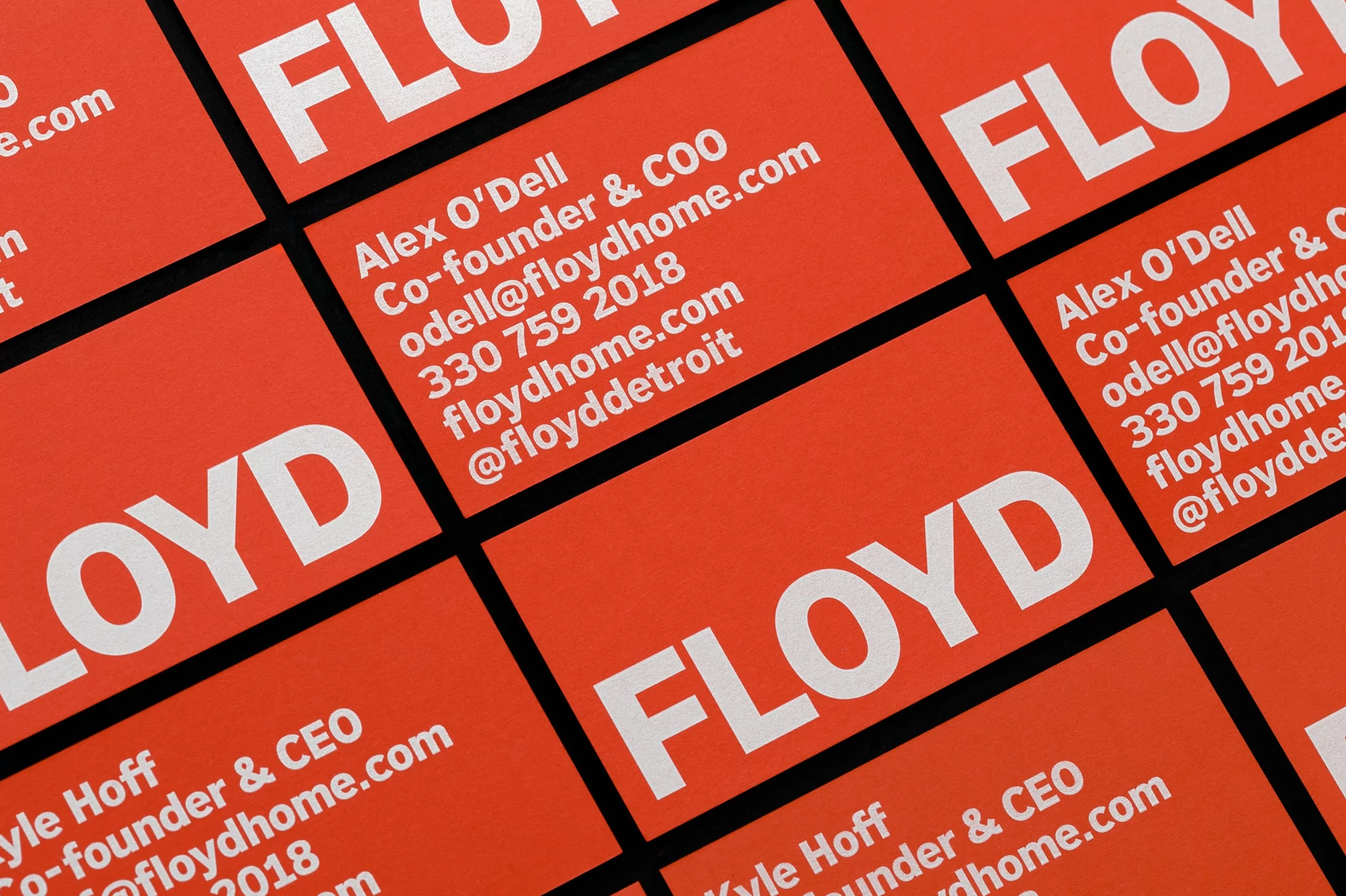 Close-up of orange and white business cards stacked with contact information, including company names and phone numbers.