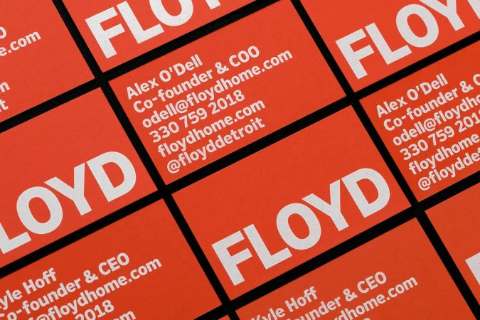 Close-up of orange and white business cards stacked with contact information, including company names and phone numbers.