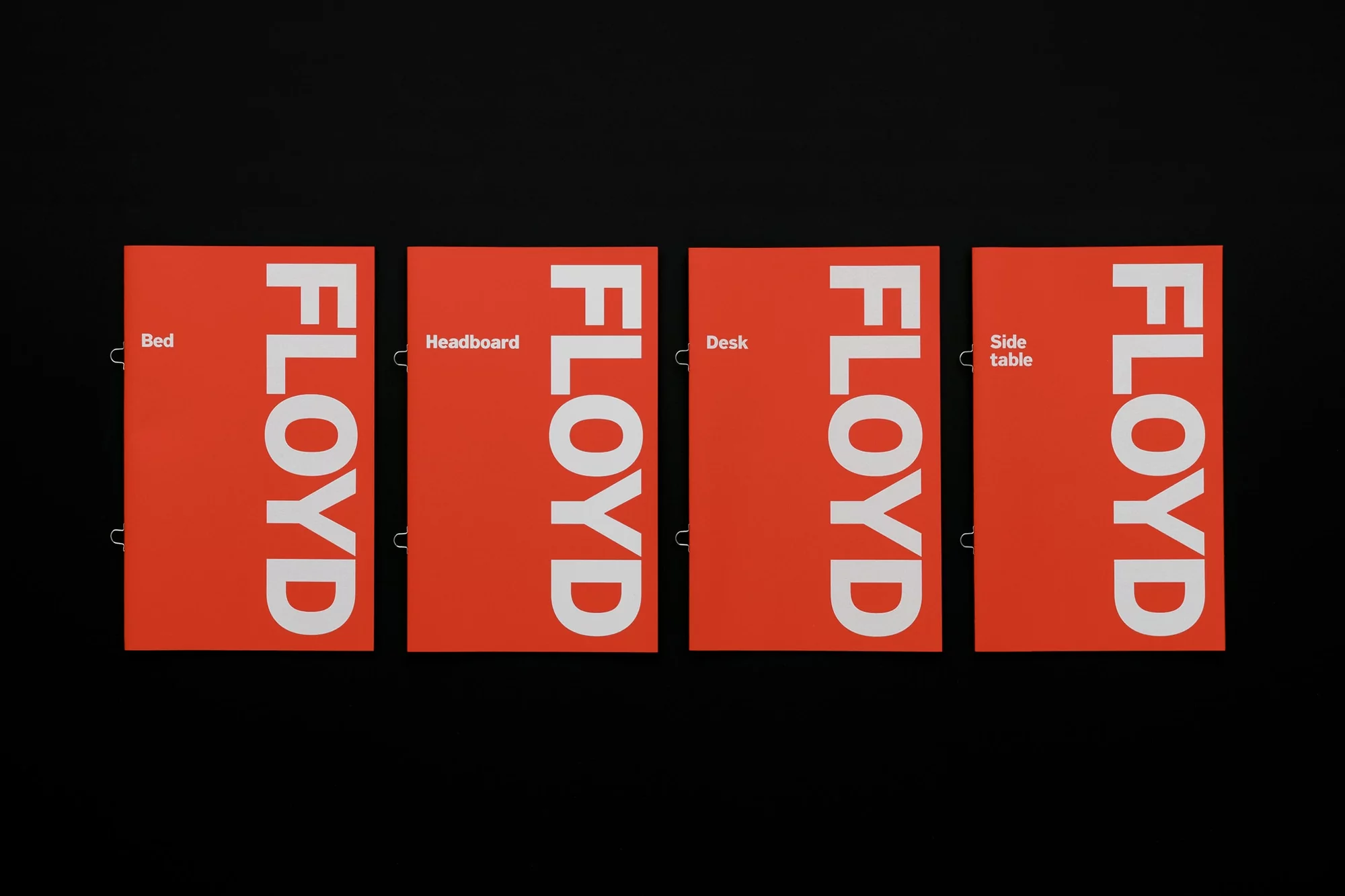Four coral-colored panels displaying 'FLOYD' vertically in white. Panels advertise furniture: bed, headboard, desk, and side table.