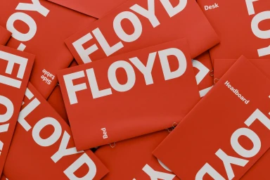 A flat lay image of bright red Floyd brand collateral cards featuring bold white typography scattered across the surface.