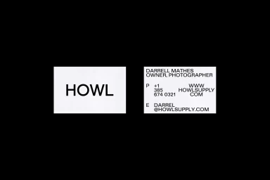 Two white business cards with black typography displayed against a solid dark background