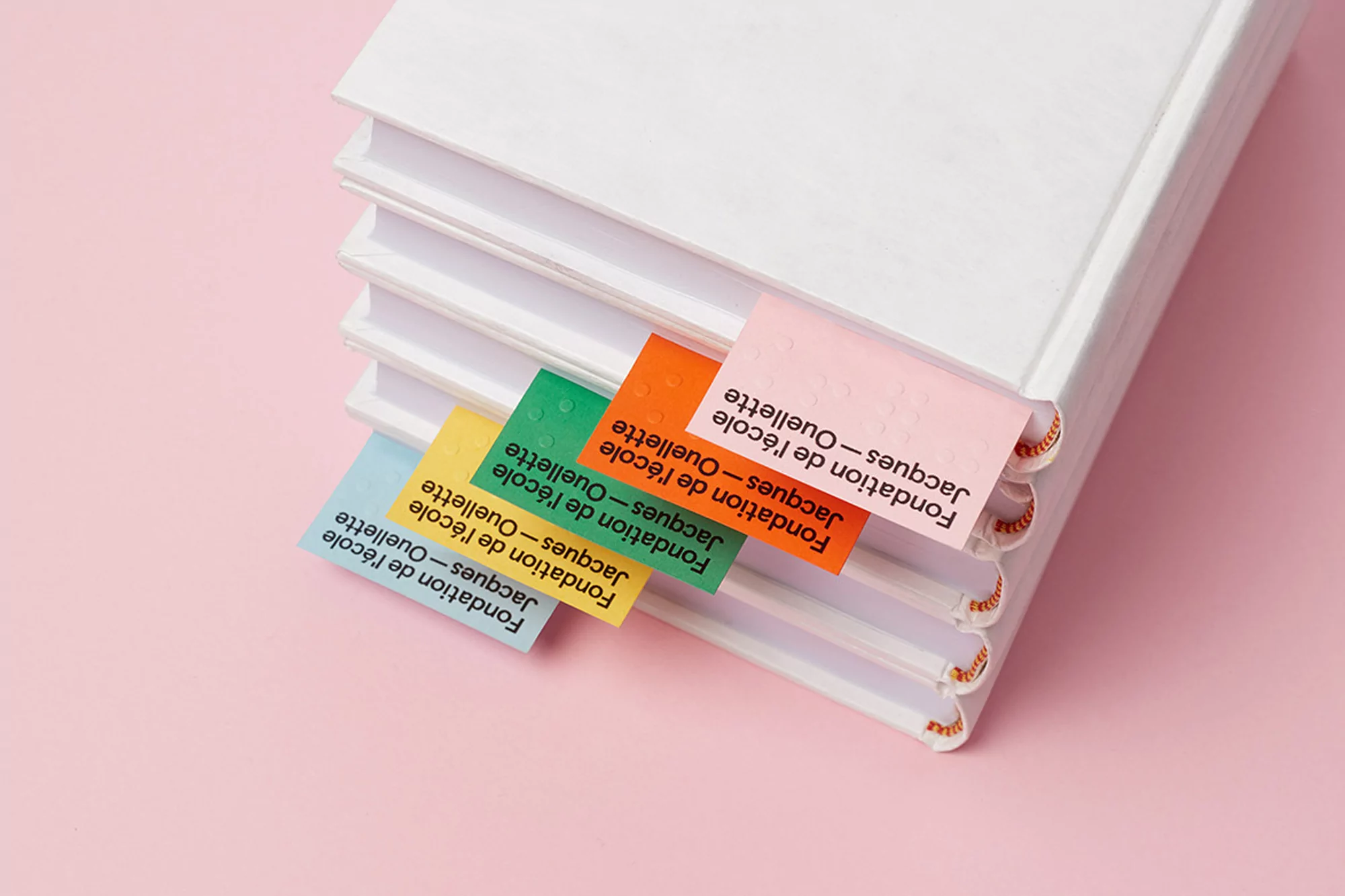 Stack of white hardcover books with colorful bookmarks on pink background. Minimalist composition, ideal for educational or library concepts.