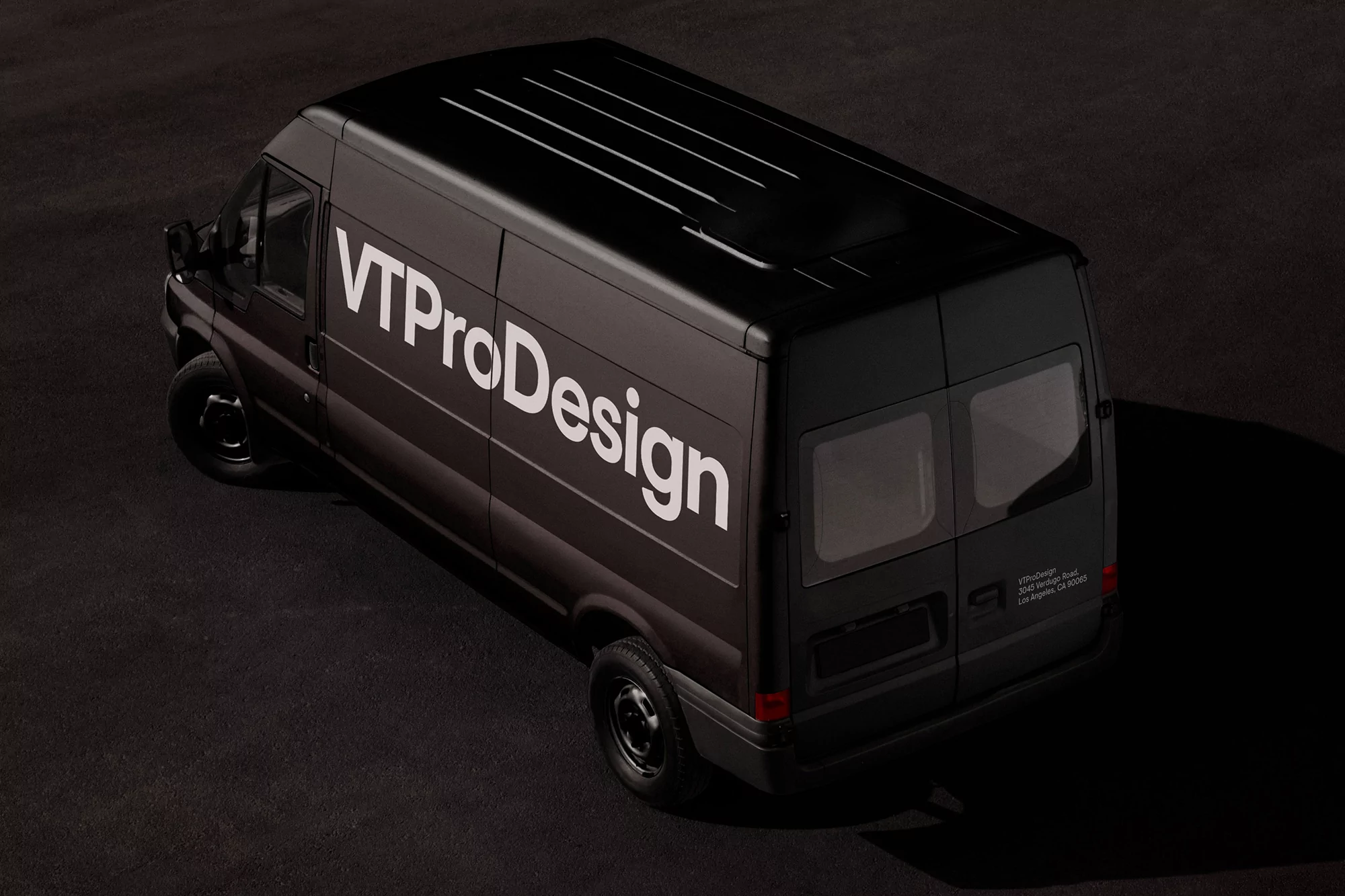 High-angle shot of a black van with 'VTProDesign' logo on a dark asphalt surface, capturing the vehicle's sleek design and branding.