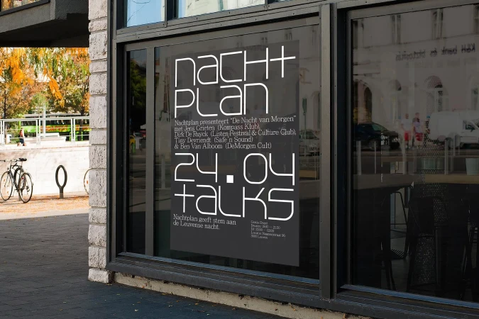 Nachtplan brand identity poster displayed on a large glass storefront window during daylight.