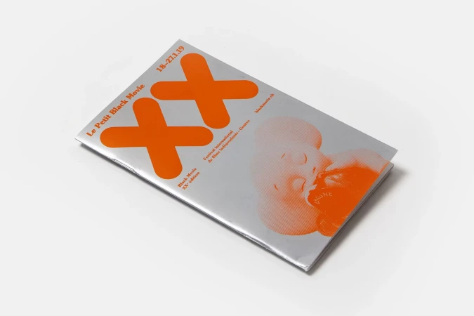 Orange graphic design magazine cover featuring abstract human face illustration on a white background in a studio setting.