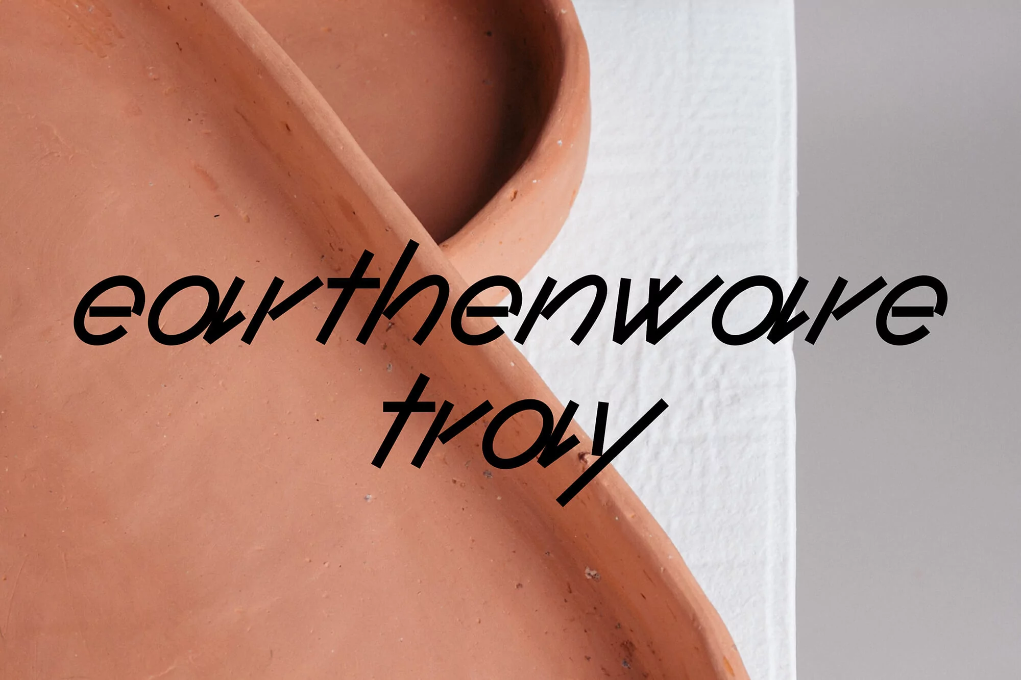 Earthenware tray on white surface. Minimalist design with a focus on texture and simple form. Warm, neutral tones and a clean aesthetic.