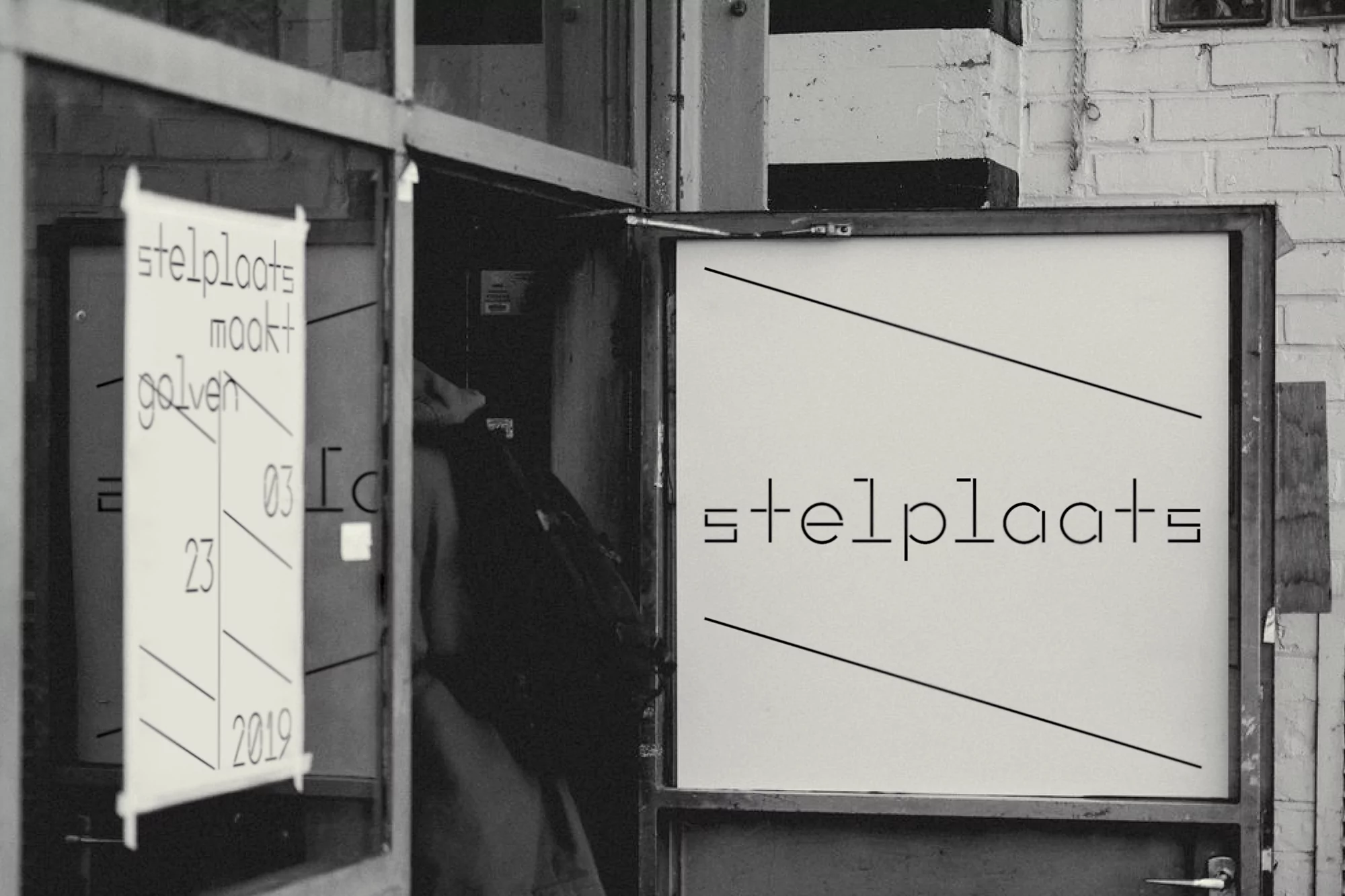 Black and white image of a person entering an art space, with posters advertising 'stelplaats maakt golven' and event details.