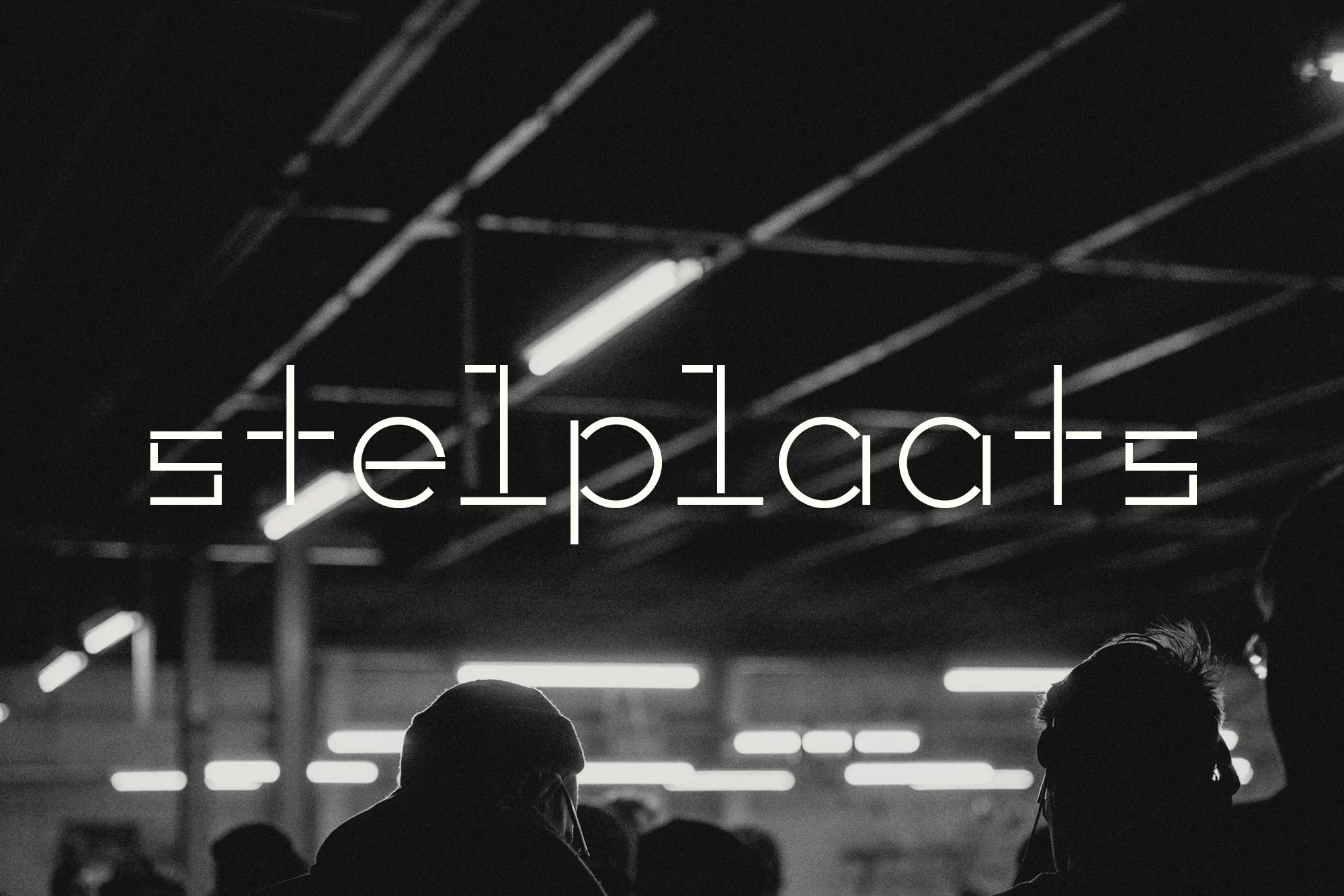Low-angle, black-and-white shot of a dimly lit interior space featuring the stylized text “stelplaats” and indistinct figures.