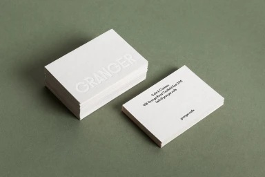 Stack of white business cards with embossed Granger lettering and single card showing cafe contact info
