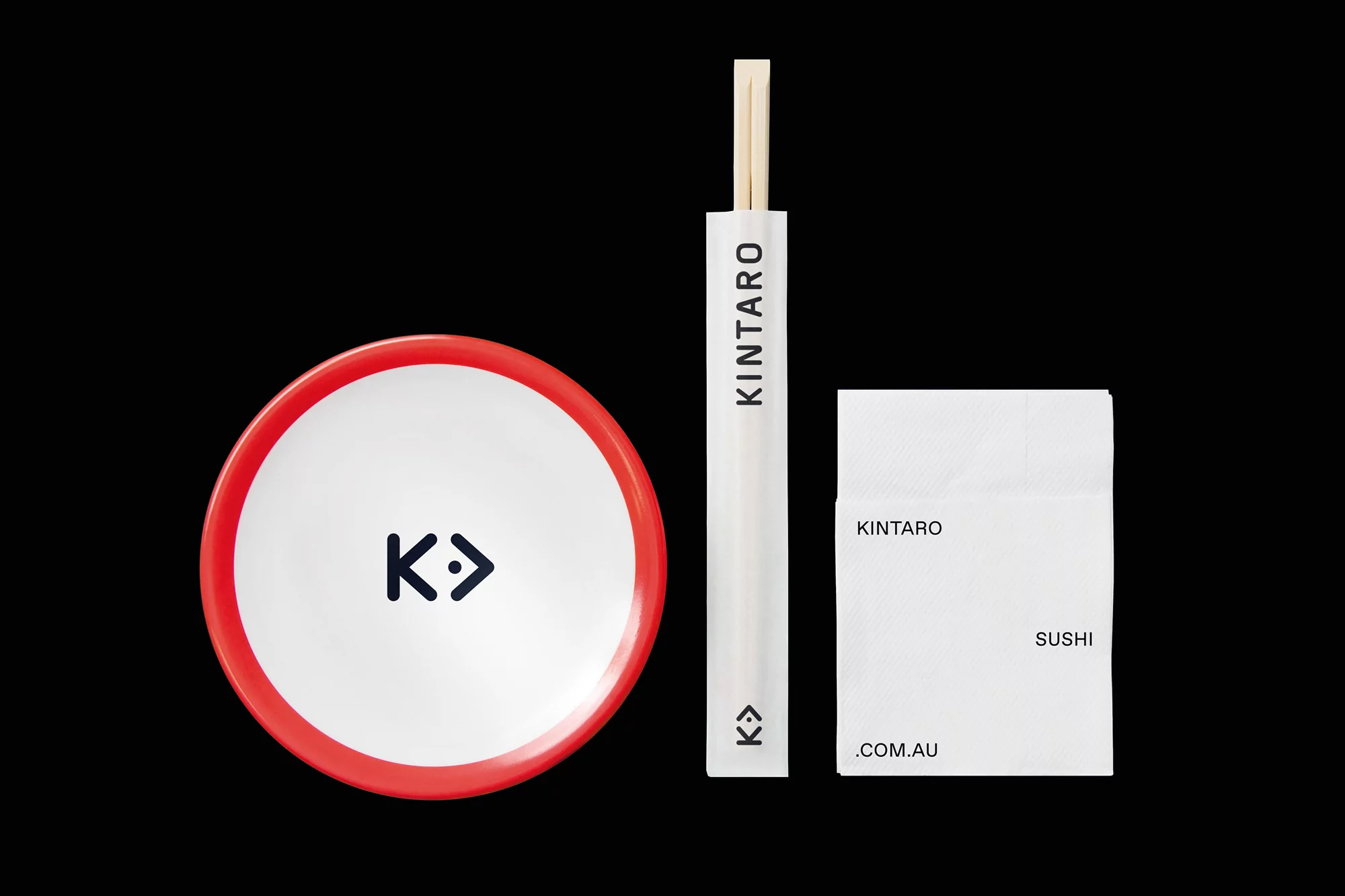 Close-up of a white plate with a red rim and a dark blue logo, a pair of chopsticks in a white wrapper, and a white paper container.