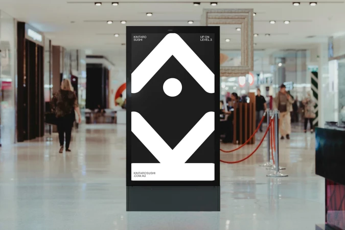 Kintaro Sushi advert in a shopping mall. The advert has an arrow design with a circle in the middle and shop details.