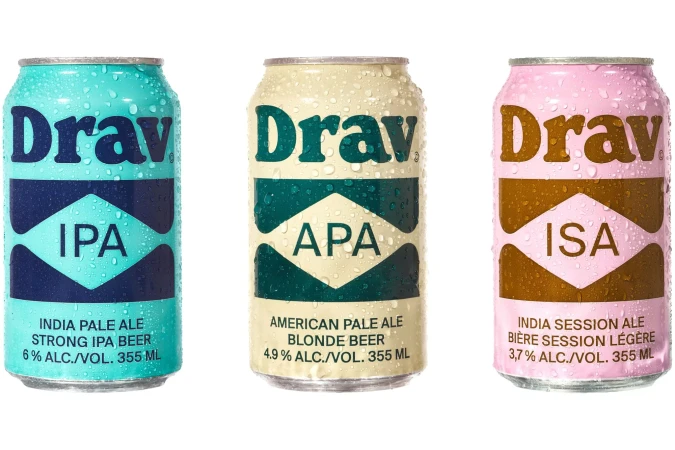 Three aluminum cans of Drav craft beer in various colors against a white background, with condensation droplets on the can surfaces.