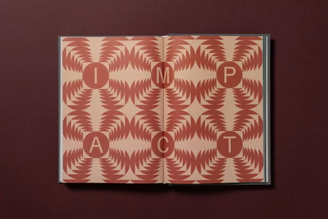 Open book with graphic pattern and the word IMPACT across two pages, on a red background. Book design with geometric shapes and letters.