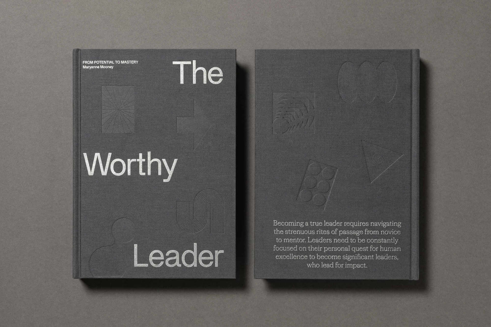 Two gray hardcover books, one titled 'The Worthy Leader' with embossed geometric designs, against a gray background. Book cover design.