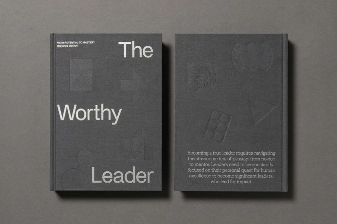 Two gray hardcover books, one titled 'The Worthy Leader' with embossed geometric designs, against a gray background. Book cover design.
