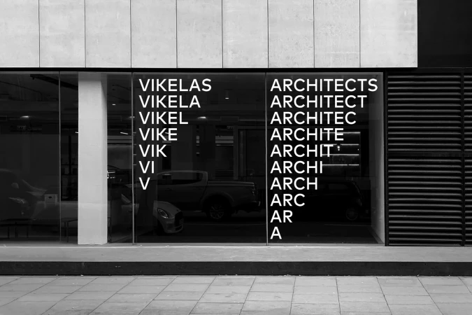 Exterior view of a building with architectural signage featuring the words 'Vikelas Architects' repeated in a graphic, modern style.