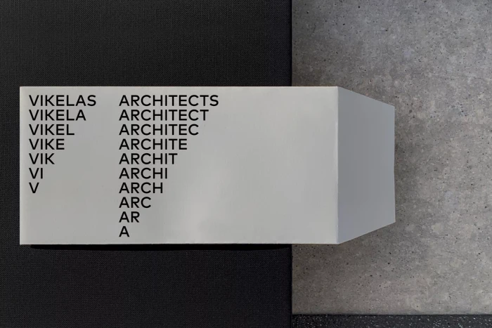 White folded dimensional logo signage for Vikelas Architects with progressive letter removal typography