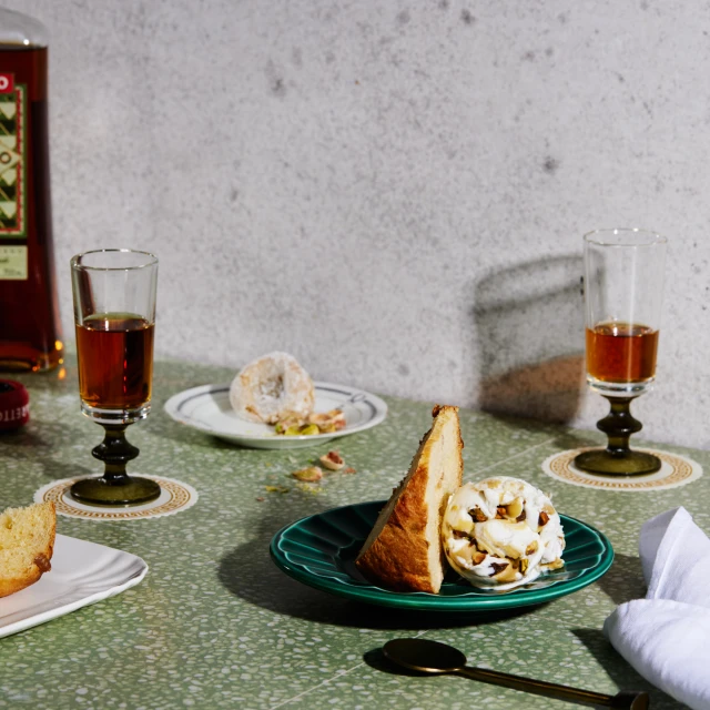 Still life photograph featuring two dessert plates with pastries and a drink, shot in eye-level and warm lighting.