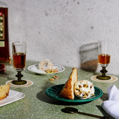 Still life photograph featuring two dessert plates with pastries and a drink, shot in eye-level and warm lighting.