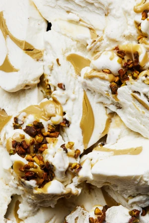 Close-up of white ice cream featuring caramel drizzle and nut pieces, highlighting textures and dessert components.