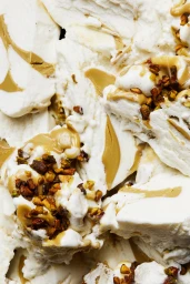 Close-up macro view of white gelato swirled with caramel and topped with chopped toasted nuts