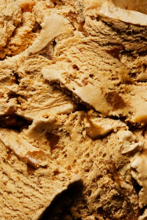 Close-up of tan-colored ice cream with swirls of caramel, creating an inviting texture and highlighting the dessert's rich flavors.