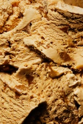 Close-up macro shot of caramel gelato showing rich textured scoops and ripples