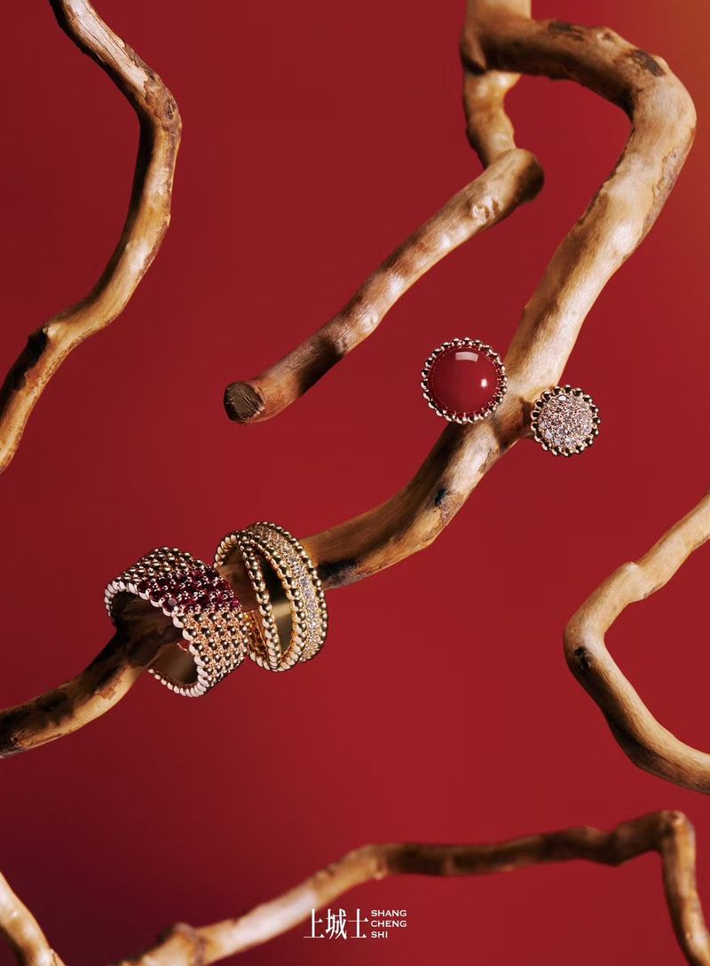 Elegant jewelry rings and earrings set against a vibrant red backdrop, displayed on the branches of a light brown tree branch.